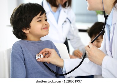 Doctor Examining A Child Patient By Stethoscope. Cute Arab Boy At Physician Appointment. Medicine And Healthcare Concept