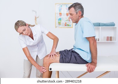 Doctor examining her patient knee in medical office - Powered by Shutterstock