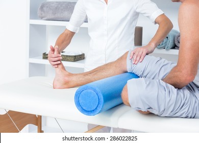 Doctor examining her patient leg in medical office