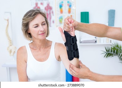 Doctor examining his patients wrist in medical office - Powered by Shutterstock