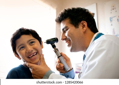 Doctor examining his young patient's ear with otoscope. - Powered by Shutterstock