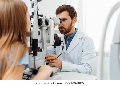 Doctor examining little girl eyes with ophthalmic equipment in modern clinic. Health care concept - Powered by Shutterstock