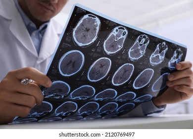 Doctor Examining MRI Images Of Patient With Multiple Sclerosis At Table In Clinic, Closeup