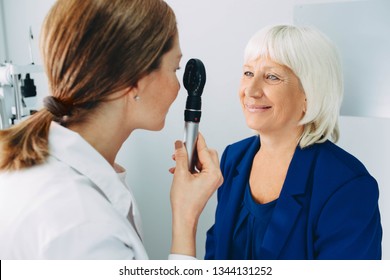 doctor examining old woman's eye with ophthalmoscope at clinic - Powered by Shutterstock