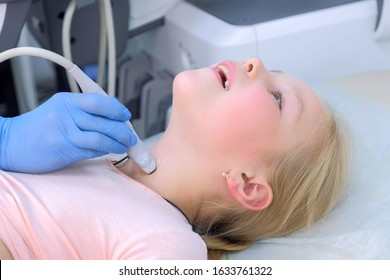 Doctor Examining Patient Child Girl Thyroid Gland Using Ultrasound Scanner Machine, Closeup View. Woman Runs Ultrasound Sensor Over Patient's Neck In Clinic. Diagnostic Examination.