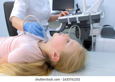 Doctor Examining Patient Child Girl Thyroid Gland Using Ultrasound Scanner Machine, Closeup View. Woman Runs Ultrasound Sensor Over Patient's Neck In Clinic. Diagnostic Examination.