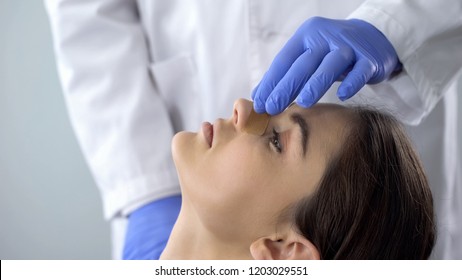 Doctor examining patient nose after rhinoplasty surgery, medical aid, healthcare