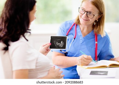 Doctor Examining Pregnant Woman. Pregnancy Check. Young Asian Female At Gynecologist Office For Prenatal Exam. Ob Gyn Showing Patient Baby Sonogram. Obstetrics And Gynecology Office.