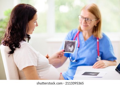 Doctor Examining Pregnant Woman. Pregnancy Check. Young Asian Female At Gynecologist Office For Prenatal Exam. Ob Gyn Showing Patient Baby Sonogram. Obstetrics And Gynecology Office.