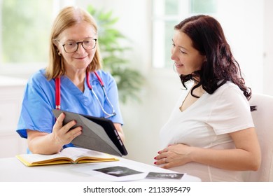 Doctor Examining Pregnant Woman. Pregnancy Check. Young Asian Female At Gynecologist Office For Prenatal Exam. Ob Gyn Showing Patient Baby Sonogram. Obstetrics And Gynecology Office.