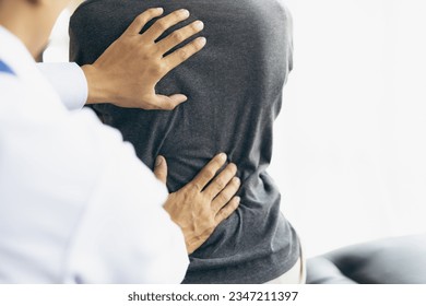 Doctor examining woman back pain in examination room. Doctor practicing back and shoulder physiotherapy for female patient in hospital. - Powered by Shutterstock