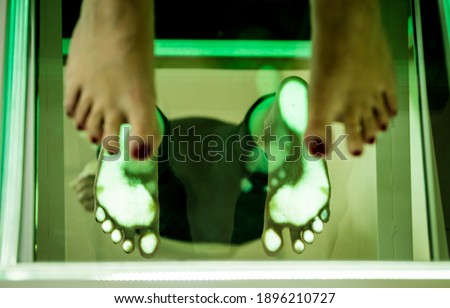 Doctor is at examining womans feet by using plantoscopy device