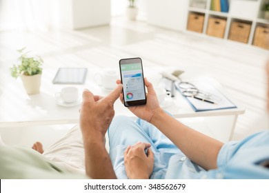 Doctor Explaining Aged Patient How To Use Calorie Counter On The Smartphone