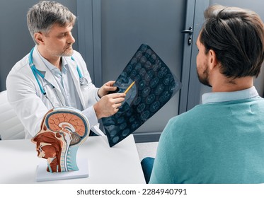 Doctor explaining to male patient results of MRI scan of his brain. Diagnosis of diseases and head injuries - Shutterstock ID 2284940791