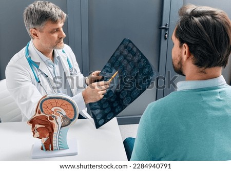 Doctor explaining to male patient results of MRI scan of his brain. Diagnosis of diseases and head injuries