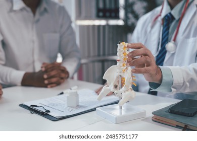 Doctor explaining spine anatomy to a patient in a hospital office. Close-up shows professional care in diagnosing spine issues - Powered by Shutterstock