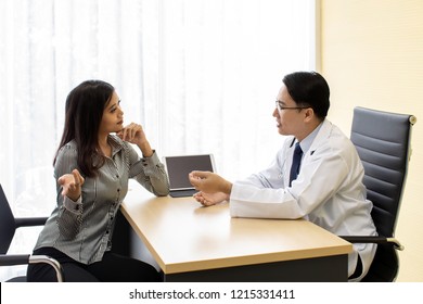 Doctor explaining treatment method to patient in beauty clinic using tablet