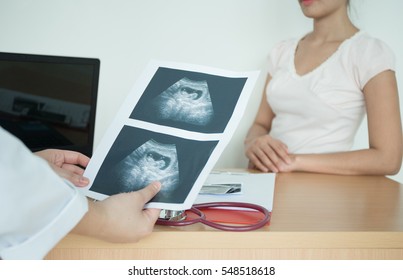 Doctor Explaining Ultrasound Scan To Pregnant Woman In Hospital.