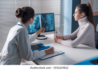 Doctor explaining a x-ray to the patient and pointing at the computer screen, the woman is wearing a cervical collar - Powered by Shutterstock