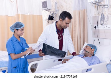 Doctor Explaining Xray To Patient While Nurse Making Reports At Hospital Ward