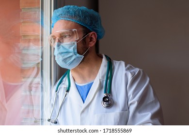Doctor with face mask looking through the window