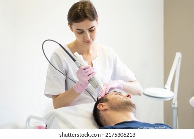 Doctor female dermatologist trichologist makes a procedure to stimulate hair growth to a patient man. Laser treatment of alopecia and hair loss - Shutterstock ID 2175306213