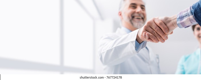 Doctor and female patient meeting at the hospital and shaking hands, healthcare and medicine banner