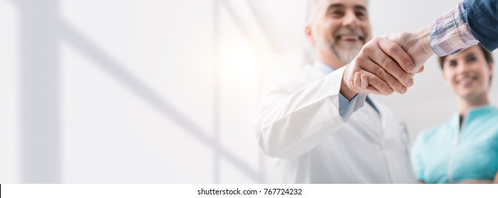 Doctor and female patient meeting at the hospital and shaking hands, healthcare and medicine banner