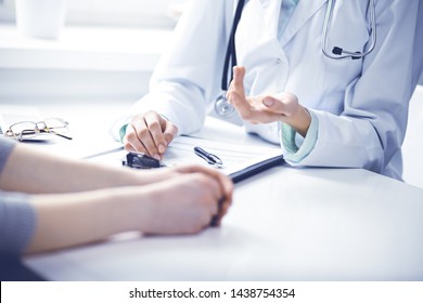 Doctor and female patient sitting at the desk and talking in clinic near window. Medicine and health care concept. Green is main color