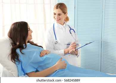 Doctor filling medical record of pregnant woman