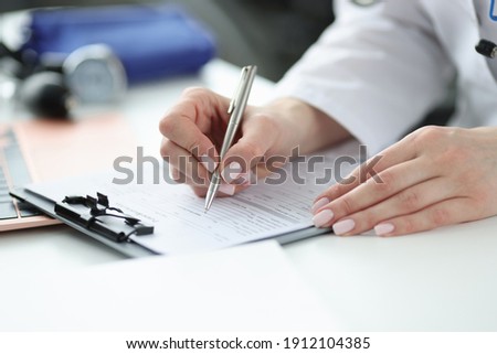 Doctor filling out patients medical history in office closeup. Collecting anamnesis concept