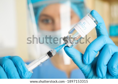 Doctor filling syringe with vaccine against Covid-19 in hospital, focus on hands