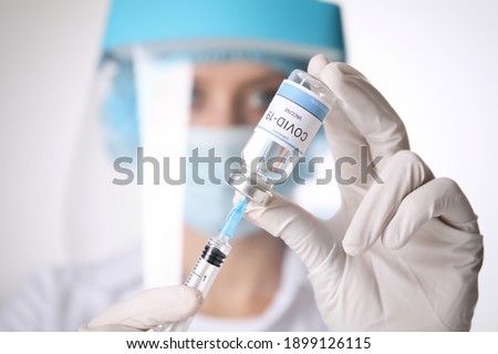 Doctor filling syringe with vaccine against Covid-19 on white background, closeup