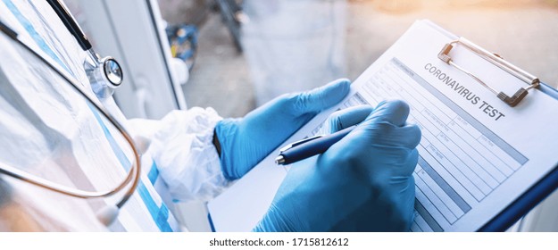 Der Arzt füllt ein Koronavirus-Testdatenblatt mit einem Pen in Schutzkleidung in einer Klinik aus, die sich an der Covid-19-Coronavirus-Epidemie gegen Fenster lehnt
