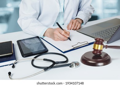 Doctor Fills Out A Legal Document In The Office At The Table.