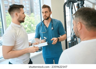 Doctor and fitness coach discussing client workout plan - Powered by Shutterstock