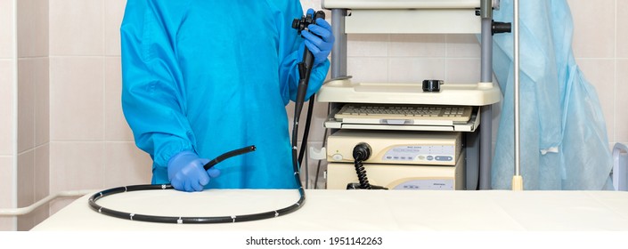 Doctor gastroenterologist in protective clothing holding endoscope before gastroscopy. Medical examination, medicine utensils and instruments, gastrointestinal fiberoptic endoscopy at modern hospital