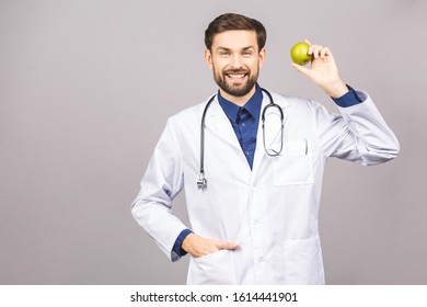 Doctor giving apple concept for healthy eating and lifestyle or good diet. A male medical doctor with stethoscope holding a green apple isolated on grey background.