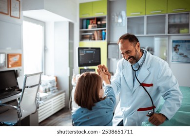 Doctor giving high five to young patient in clinic - Powered by Shutterstock