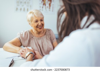 Doctor giving hope. Close up shot of young female physician leaning forward to smiling elderly lady patient holding her hand in palms. Woman caretaker in white coat supporting encouraging old person - Powered by Shutterstock