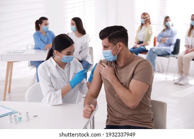 Doctor giving injection to patient while other waiting in line at hospital. Vaccination campaign - Shutterstock ID 1932337949