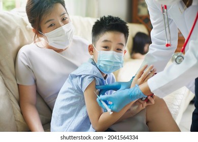 Doctor Giving An Injection Vaccine To An Asian Boy. Child And Mother Wearing Face Mask. Covid19 Vaccination Shot For Child.Thai Preschooler Getting Vaccine Immuization.Pandemic In Asia.