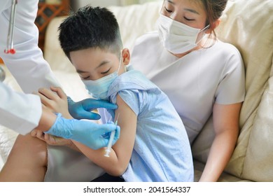 Doctor Giving An Injection Vaccine To An Asian Boy. Child And Mother Wearing Face Mask. Covid19 Vaccination Shot For Child.Thai Preschooler Getting Vaccine Immuization.Pandemic In Asia.