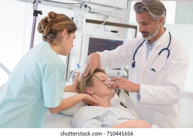 Doctor Giving Oxygen Mask To Female Patient At Hospital