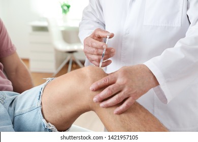 Doctor giving patient injection in clinic, closeup. Knee problem treatment