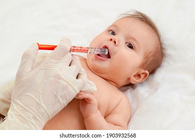 Doctor giving remedy to baby. Cute baby gets medicine with a syringe in his mouth. Baby health concept