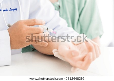Doctor giving steoid or drug injection to patient ‘s hand for treatment carpal tunnel or median nerve compressive neuropathy disease.Orhopedic doctor in white gown holding syringe in hand. 