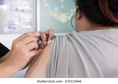 Doctor giving vaccination in arm of young asian woman, bacteria and virus.Wuhan coronavirus (COVID-19) outbreak and pandemic prevention,personal hygiene concept. - Shutterstock ID 672113446