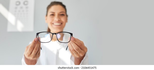 Doctor Giving You New Prescription Glasses. Happy Optometrist Showing Modern Good Quality Eyeglasses. Optometry, Eyewear, Eye Health Concept. Grey Text Copyspace Banner Background, Closeup, Close Up