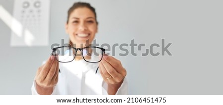 Doctor giving you new prescription glasses. Happy optometrist showing modern good quality eyeglasses. Optometry, eyewear, eye health concept. Grey text copyspace banner background, closeup, close up